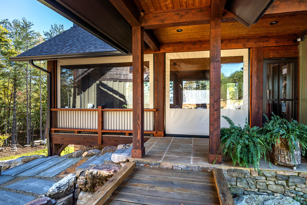 Clear motorized screen enclosing a timber-framed covered porch surrounded by Oregon forest