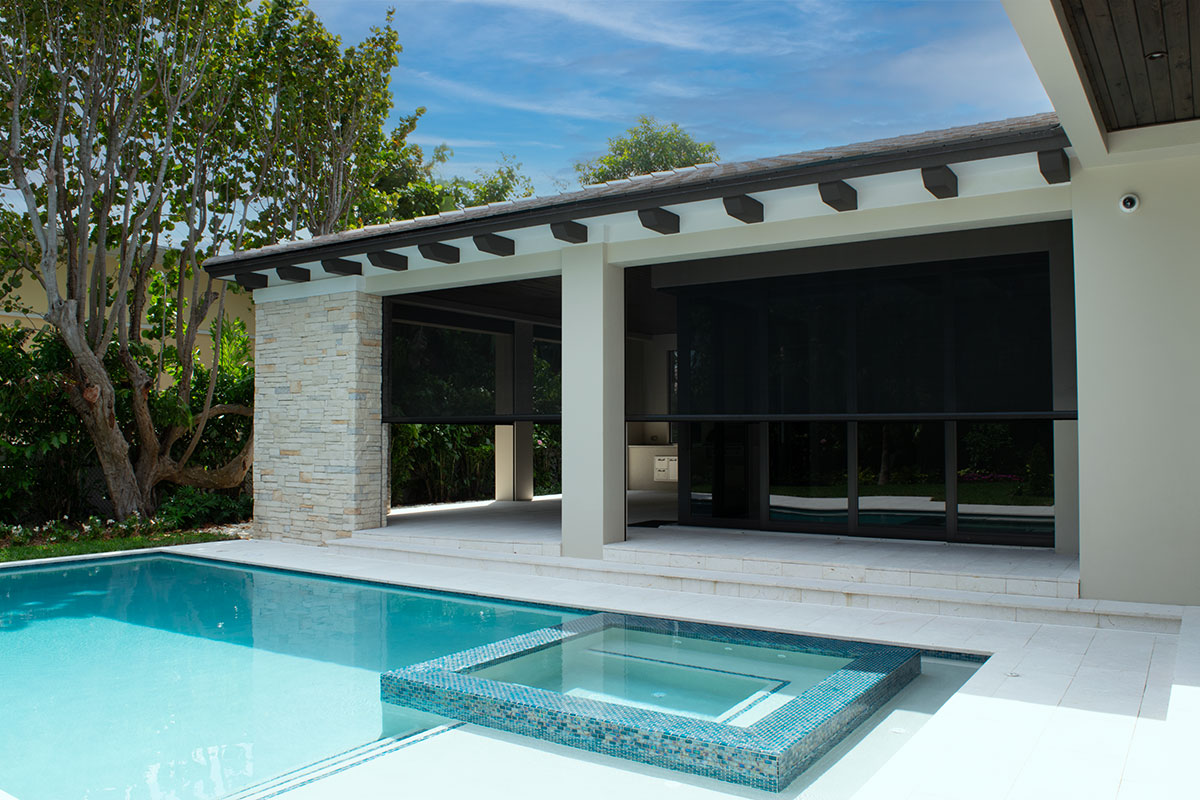 Dark motorized insect screens lowered across a poolside covered patio