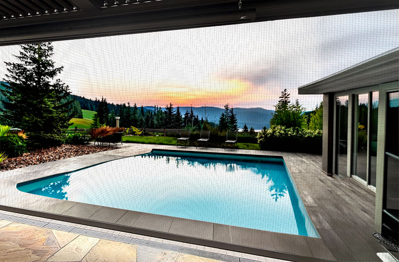 Fenetex motorized screens shading a poolside patio at sunset